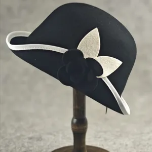 Elegant black wool bucket hat with white trim and delicate camellia flower decoration for women.