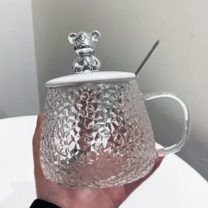 Glass coffee cup detail showcasing textured hammer pattern body and cute silver bear lid.