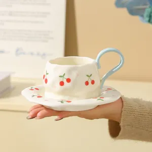 Handmade ceramic coffee cup and saucer set with cute cherry pattern for afternoon tea time.