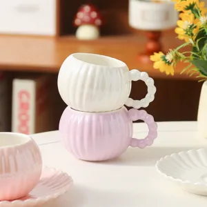 Set di tazza da caffè e piattino in ceramica, vista dettagliata di tazze rosa e bianche impilate.