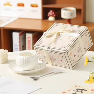 Dettaglio tazza caffè in ceramica e piattino, graziosa scatola regalo rosa per tè pomeridiano.