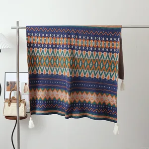 Detailed shot of the bohemian knitted blanket hanging on a metal rack with decorative tassels.