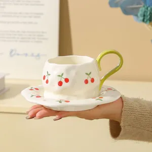 Close-up detail of ceramic coffee cup with cute cherry print and green handle for tea.