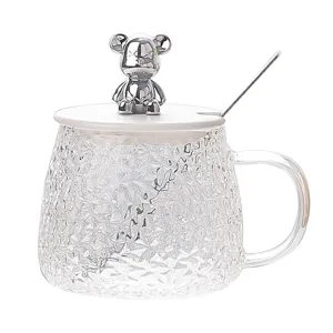 Clear hammered glass coffee mug with white lid, spoon and silver trendy bear figurine top.