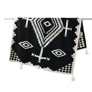 Bohemian black and white knitted sofa throw blanket with geometric pattern and tassels.