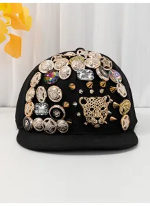 Primo piano del cappellino nero con visiera piatta, leopardo oro e bottoni di cristallo.