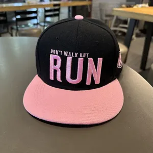 Primer plano detallado de una gorra snapback hip-hop negra y rosa con bordado.
