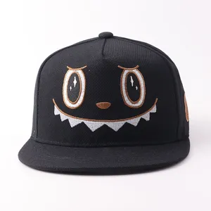 Detalle gorra hip-hop negra, diseño cara de monstruo bordado, visera plana.
