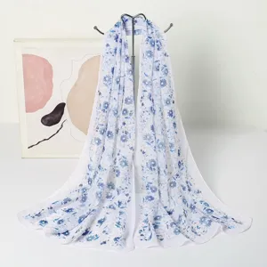 Detailansicht eines leichten Chiffonschals mit elegantem blauem Blumendruck auf weißem Stoff