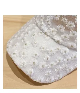 Close-up detail of women's white mesh baseball cap featuring delicate daisy embroidery.