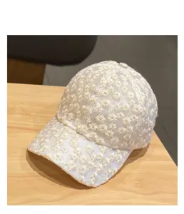 Detailed view of white lace baseball cap featuring delicate small daisy embroidery and breathable design.