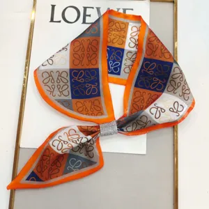 Close-up of a stylish narrow silk scarf with vibrant color block pattern and rhinestone buckle.