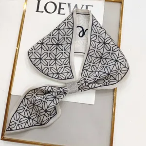Detail view of a chic black and white geometric silk narrow scarf with a sparkling rhinestone buckle.
