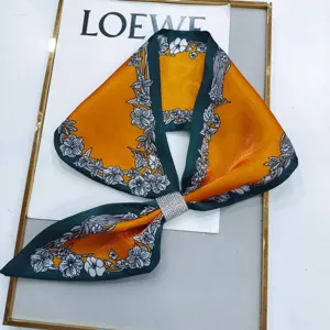 Detailed view of women elegant long silk scarf with rhinestone buckle and floral pattern print.