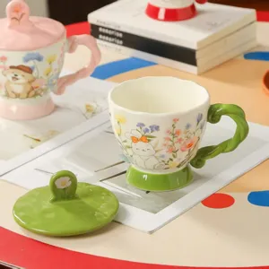 Detailaufnahme einer Keramiktasse mit Hasenmotiv, grünem Henkel und passendem Deckel.