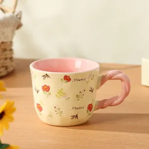 Charming ceramic coffee mug with cute floral print, pink interior and twisted handle detail.