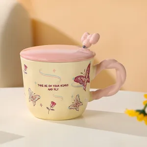 Dettaglio tazza in ceramica con motivo farfalla, manico rosa e cucchiaio con fiocco.