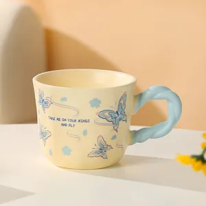 Dettaglio ravvicinato della tazza in ceramica con motivo a farfalla e manico intrecciato.