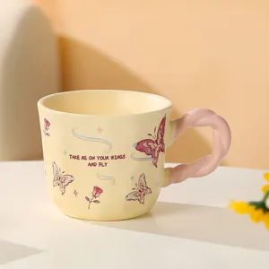 Dettaglio di una tazza in ceramica giallo pastello con farfalle e un manico rosa ritorto.