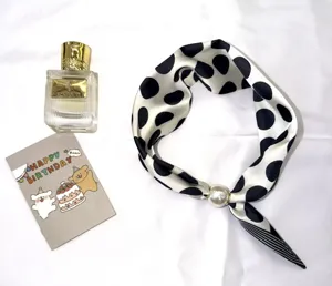 Vue détaillée du foulard en soie à pois noirs et blancs avec boucle magnétique en perle.