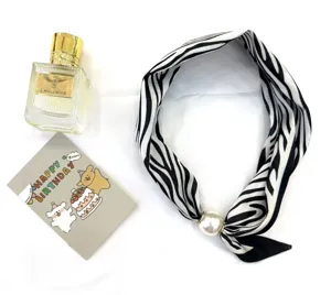 Détail foulard en soie motif zèbre avec grosse boucle aimantée perle, tour de cou chic.