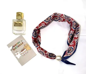 Vue détaillée du foulard en soie à imprimé floral rouge avec un grand fermoir aimanté en perle.