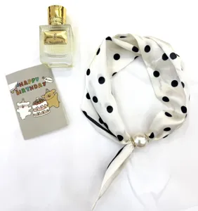 Foulard en soie à pois chic avec fermoir aimanté en perle, détail d'accessoire.