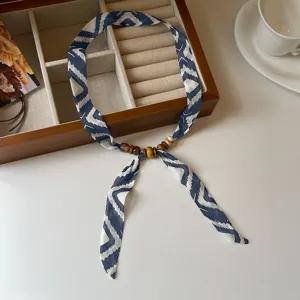 Detailed close-up view of the blue patterned silk scarf necklace featuring wooden beads.