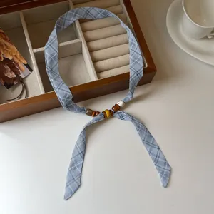 Close-up of a blue plaid silk scarf necklace featuring delicate wooden beads and elegant design.