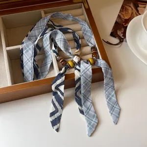 Chic blue plaid fabric ribbon necklace detail featuring decorative wooden and ceramic beads.