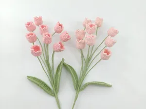 Handmade crochet pink flower bouquet detail, delicate yarn craft with green stems and leaves.