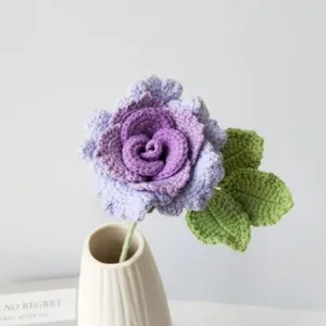 Handmade crochet purple rose flower with green leaves in a white ceramic vase detail shot
