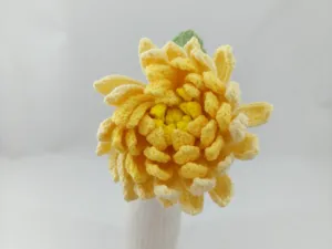 Gros plan détaillé d'une fleur de dahlia crochetée jaune artisanale à la texture de laine fine.