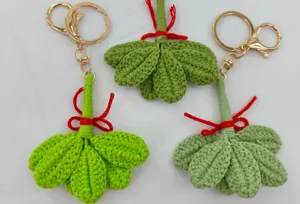 Handcrafted crochet green leaf keychain detail, showing intricate yarn texture and gold hardware rings.