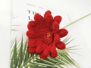 Handcrafted crochet red gerbera daisy flower detail, soft yarn handmade bouquet display.
