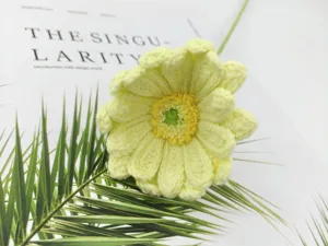 Handcrafted crochet gerbera daisy wool flower, detailed view of yellow handmade floral decor.