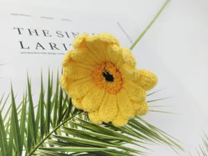Handmade crochet yellow gerbera flower close-up detail, realistic knitted floral decor.