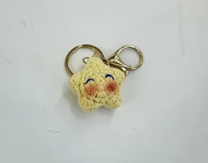 Detalle de llavero de estrella de ganchillo hecho a mano, colgante de bolso amarillo con metal.
