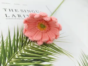 Handmade crochet pink gerbera daisy flower detail, artificial wool flower bouquet close-up view.