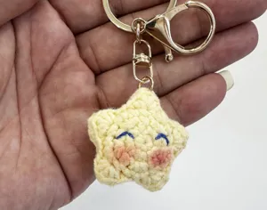 Detalle de llavero de estrella de ganchillo hecho a mano, dije de felpa amarillo oro.
