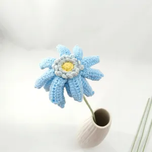 Détail de fleur au crochet faite main, gerbera en laine bleue dans un vase en céramique blanche.
