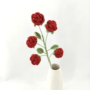 Handcrafted crochet multi-head red rose bouquet with green leaves in a white ceramic vase detail.