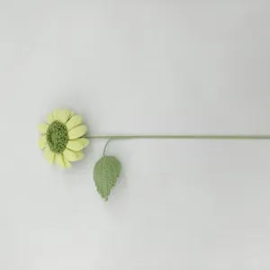 Détail de tournesol au crochet fait main, artisanat floral en laine, tige et feuille délicates.