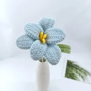 Handcrafted crochet blue flower with yellow stamen in a ceramic vase detail view.