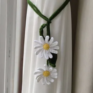 Handmade crochet daisy curtain tie-back with green vines, elegant home decor detail.