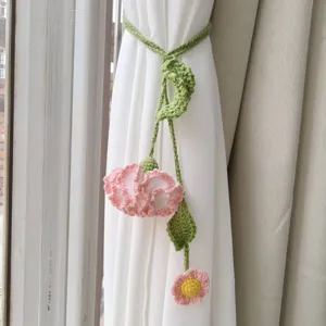 Handmade crochet flower curtain tieback detail, knitted pink carnation and green leaf vine.