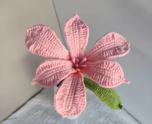 Handmade crochet pink flower close-up detail, delicate yarn texture home decor table ornament.