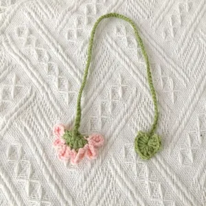 Handmade crochet flower bookmark detail showing delicate pink bloom and green stem.