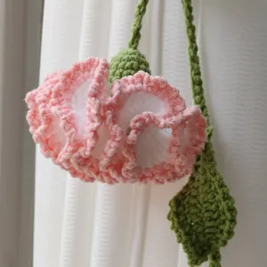 Handmade crochet pink flower curtain tieback close up, charming knitted home decor accessory.