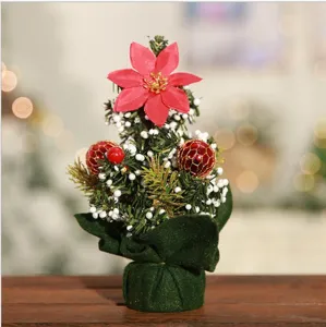 Vue détaillée du mini sapin de Noël de table, avec poinsettia rouge et boules décoratives.